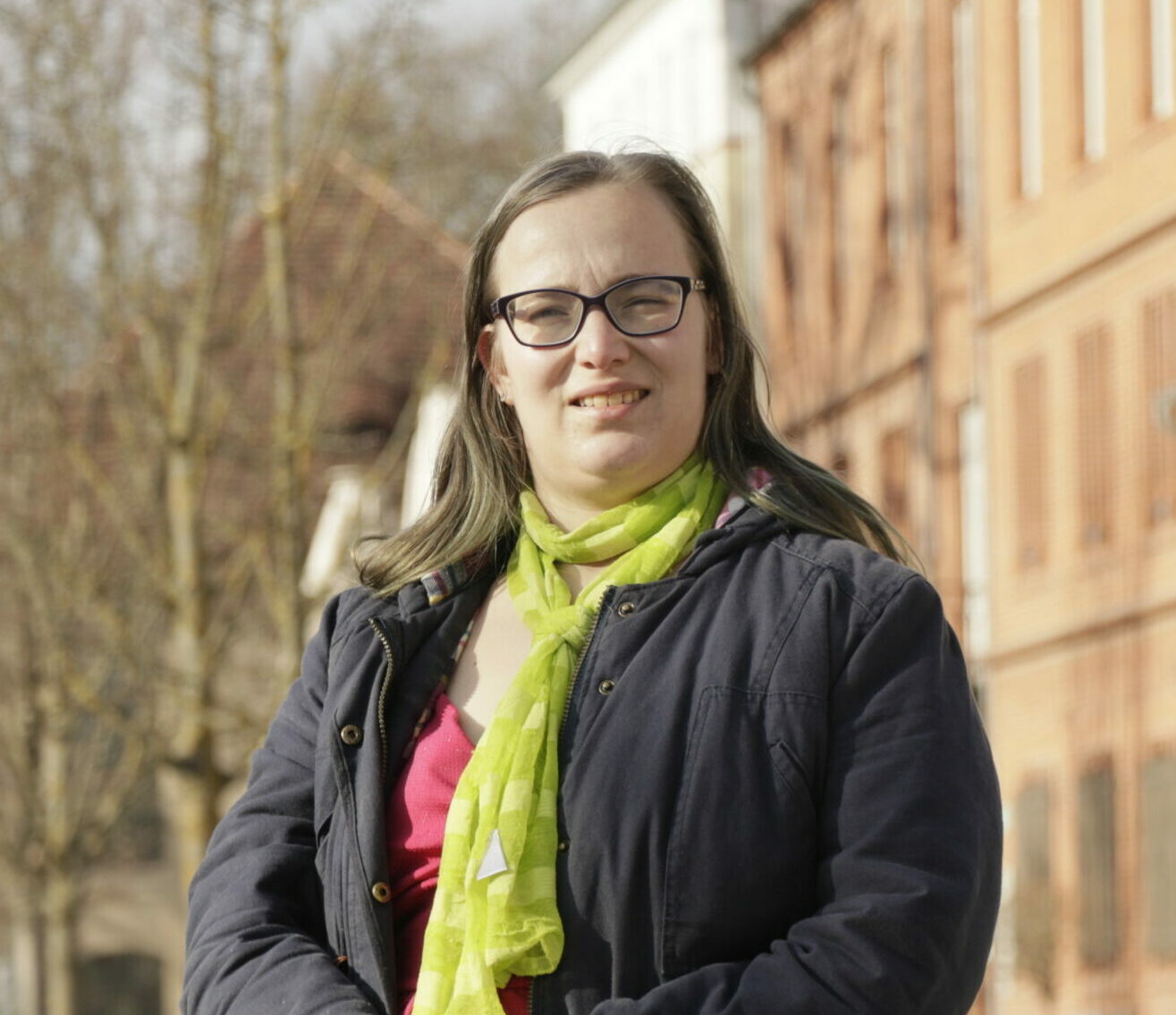 Marie Richter, stehend vor Häusern und Bäumen im Hintergrund